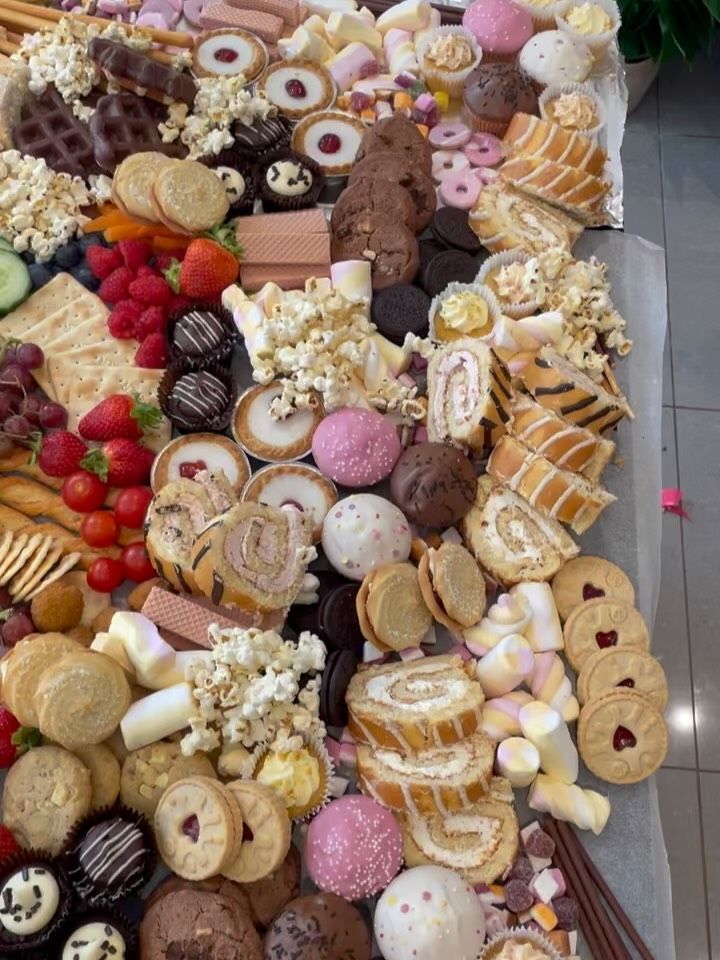 A sweet grazing table piled with Swiss rolls, Jammie Dodgers, cupcakes, marshmallows and popcorn